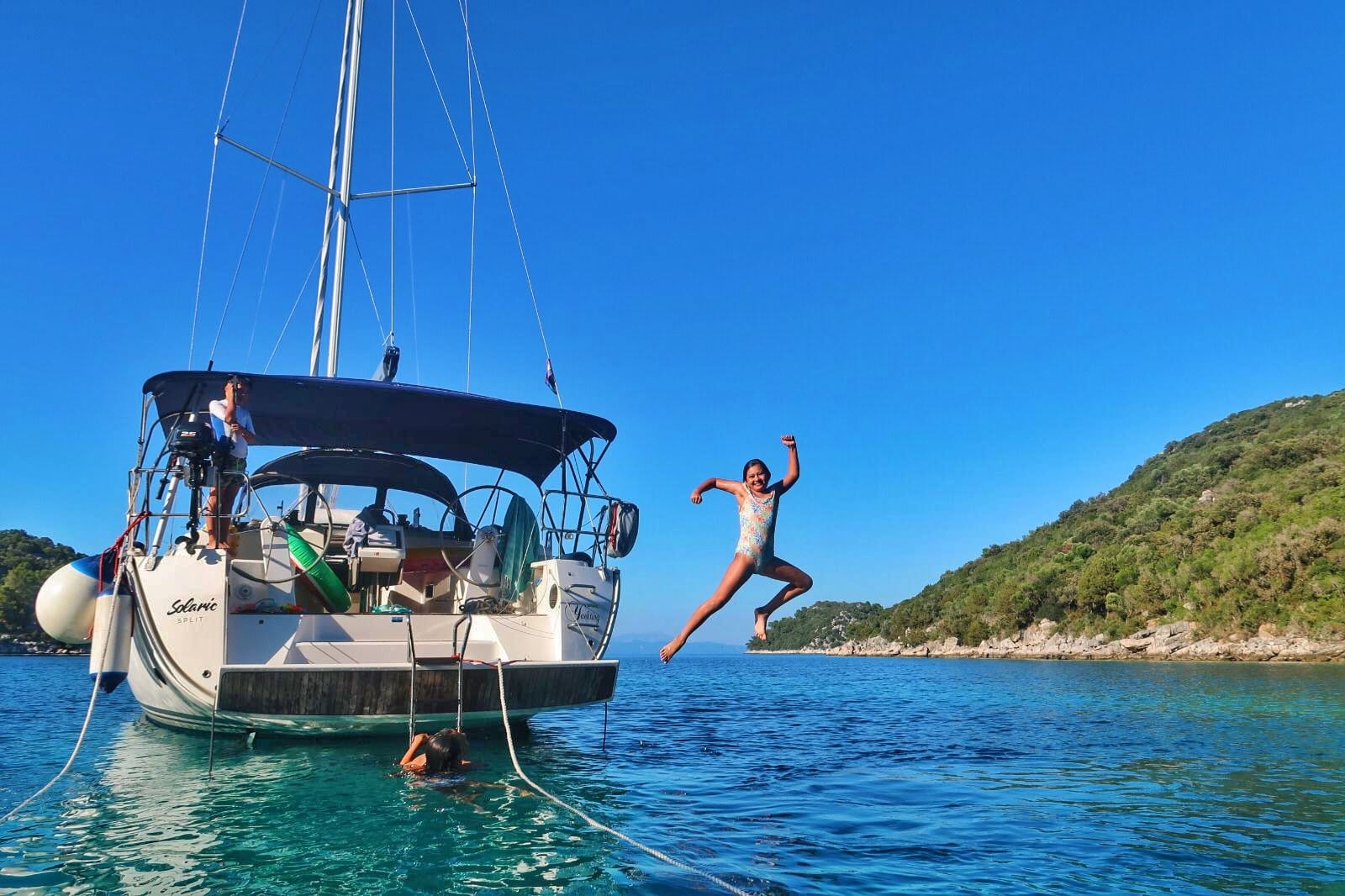 Children jumping in the sea from the yacht on a sailing vacation in Croatia